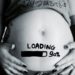90%-loading-baby recorte de uma barriga de uma gestante, mostrando a barriga pintada nela a palavra "loading" uma barra em preto quase completa e "90%", a mulher com as mãos na barriga. um pedaço da camiseta da mulher dá para ver a palavra "namasté" uma dica de como sobreviver ao último mês de gestação; mantenha a calma